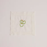 Single white cocktail napkin embroidered with three green olives and red pimento detail.